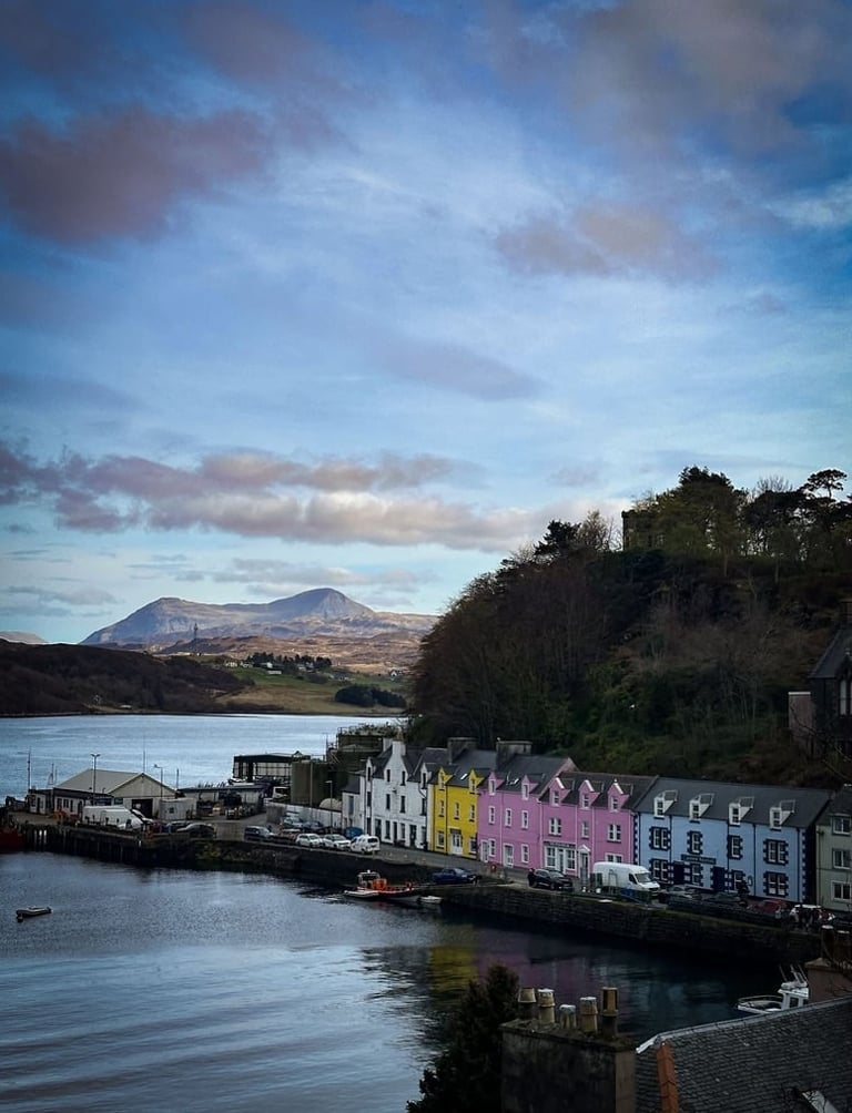 Colorful waterfront village with mountains in background under dramatic cloudy sky