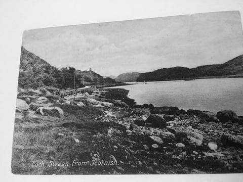 Black and white vintage photograph of a Scottish loch surrounded by mountains and rocky shoreline