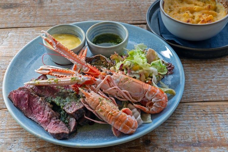 Grilled seafood platter with sliced steak, lobster, shrimp, and fresh greens